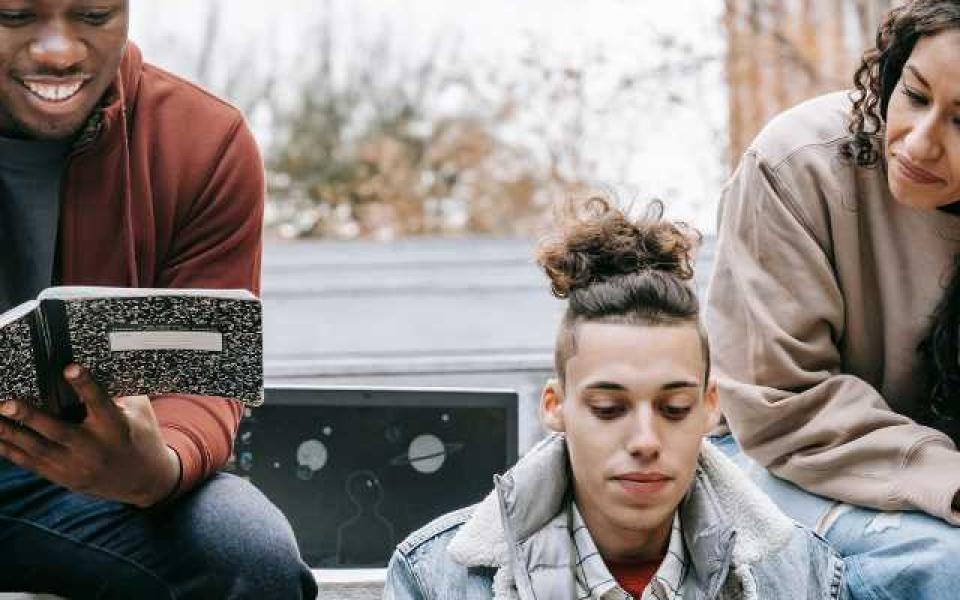 Young people together outside on their laptops