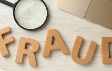 Fraud spelt out in wooden letters, with a magnifying glass next to it